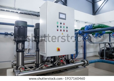 Water pump station and pipeline with tanks in an industrial room to supply high pressure water for firefight tasks. Sprinkler pipes and control system to provide drink water to people in building Royalty-Free Stock Photo #1937160460