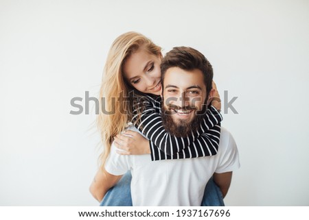 Happy to be together. Handsome young man piggybacking beautiful woman and smiling