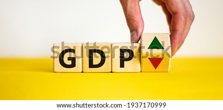 GDP, gross domestic product symbol. Businessman holds a cube with up and down icon. Word 'GDP'. Beautiful white background. Copy space. Business and growth of GDP, gross domestic product concept.