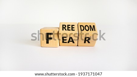 Freedom from fear symbol. Turned wooden cubes and changed the word 'fear' to 'freedom'. Beautiful white background, copy space. Business, motivational and freedom from fear concept.