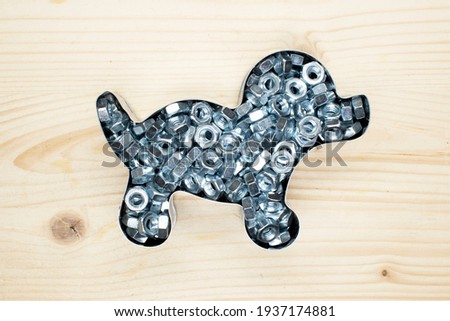 metal outline of the dog covered with nuts on the background of a light board