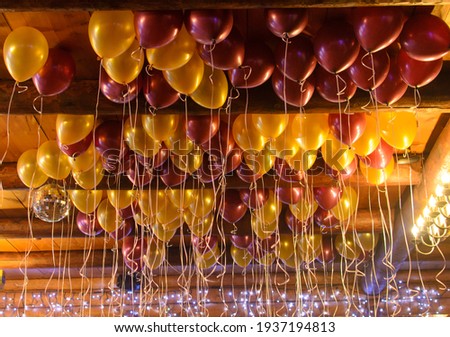 gold and burgundy balloons floating on the ceiling