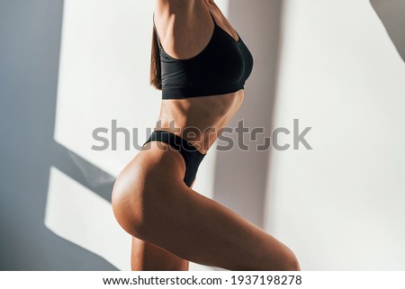 Sportive body type. Young caucasian woman is indoors at daytime.