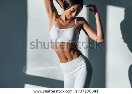 Shows her body. Young caucasian woman is indoors at daytime. Royalty-Free Stock Photo #1937198341