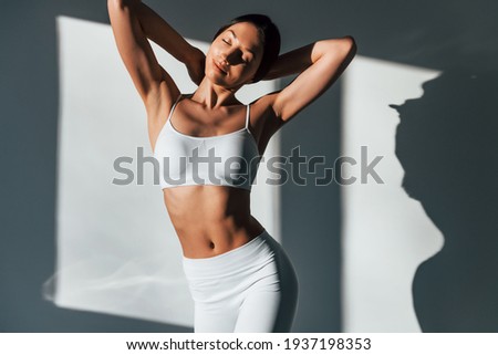 Shows her body. Young caucasian woman is indoors at daytime. Royalty-Free Stock Photo #1937198353
