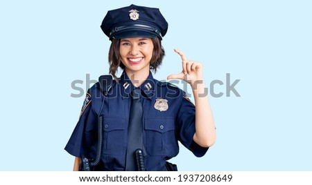 Young beautiful girl wearing police uniform smiling and confident gesturing with hand doing small size sign with fingers looking and the camera. measure concept. 