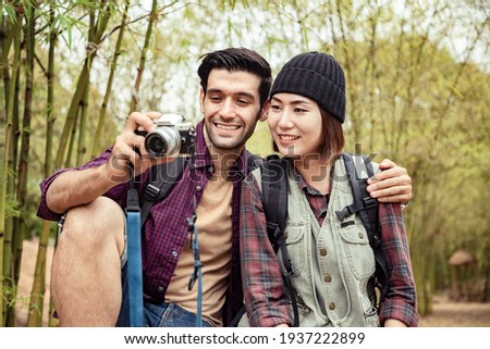 Handsome man and girlfriend using camera and take a photo in the bamboo park, Healthy body posture with happy feeling in the morning. Lifestyle and backpack concept.