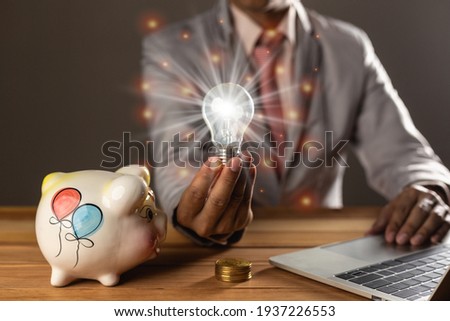 The best idea for the business concept- digital market, businessman holding on a light bulb, Finance, Savings, working with laptop and tablet on wooden table, digital business concept.