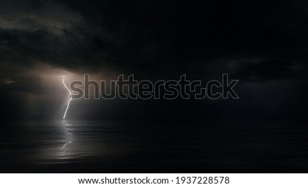 Dark mysterious monsoon cyclone storm clouds and multiple bolts of lightning. Tranquil eye of the storm above tropical Ocean at night. Conceptual establishing shot of powerful hurricane weather. Royalty-Free Stock Photo #1937228578