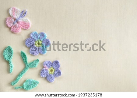 On a light yellow background is a floral arrangement of crocheted products. Imitation of a spring or summer sunny day with flowers and butterflies Royalty-Free Stock Photo #1937235178