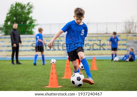 Boys attending soccer training on school field. Young man coaching children on physical education class. Soccer practice for children Royalty-Free Stock Photo #1937240467
