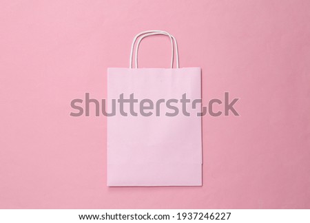 Paper shopping bag on pink pastel background. Top view