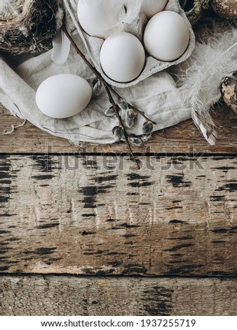 Easter rustic flat lay. Natural easter eggs, feathers, pussy willow branches, bird nest on rustic cloth on aged wooden table. Space for text. Stylish easter rural still life, brown and grey colors