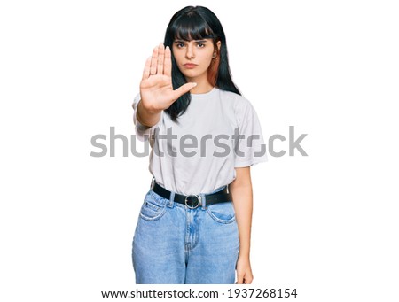 Young hispanic girl wearing casual clothes doing stop sing with palm of the hand. warning expression with negative and serious gesture on the face. 