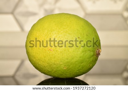 One ripe organic lime, close-up, on a tile background.