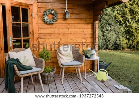 Nice wooden hut in a green garden. Garden shed with chairs and flowers. Spring mood. Drinking tea outside in spring.  Royalty-Free Stock Photo #1937272543