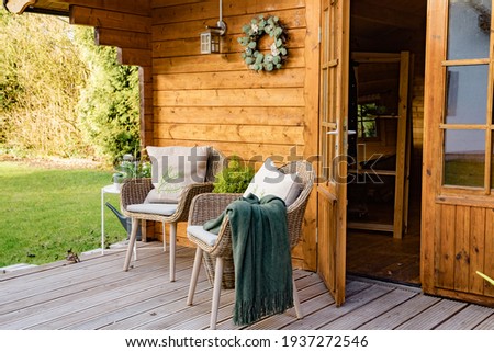 Nice wooden hut in a green garden. Garden shed with chairs and flowers. Spring mood. Drinking tea outside in spring.  Royalty-Free Stock Photo #1937272546