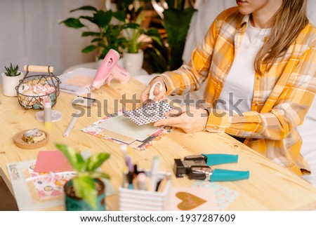 Cropped shot of women making homemade scrapbooking album from paper. DIY, hobby concept, gift idea, decor with handcraft attributes, home production, the process of creation, creativity.