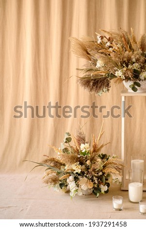 Decorations from dry beautiful flowers in a white vase on a beige fabric background. Home room decoration