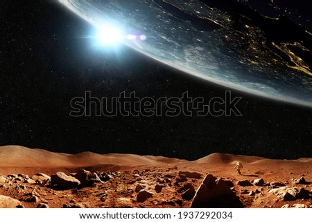 Red planet Mars with stars and planet Earth, journey space concept. Space man astronaut walks through the red desert with mountains overlooking space. Royalty-Free Stock Photo #1937292034