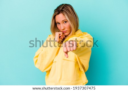 Young mixed race woman isolated on blue background throwing a punch, anger, fighting due to an argument, boxing.