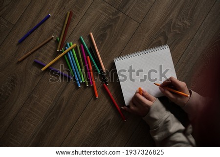 Felt pens on the floor and a felt-tip pen in hand.