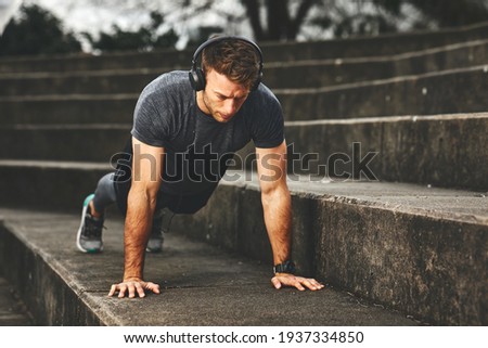 Young fit man doing push-ups outdoors on concrete steps Royalty-Free Stock Photo #1937334850