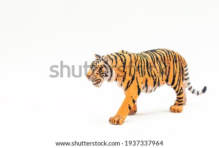 A toy tiger, a miniature model of an animal on a white background. Symbol of the year