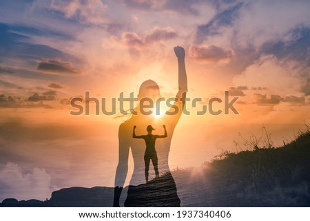 Strong successful woman on a mountain flexing arms feeling inspired, and motivated. Royalty-Free Stock Photo #1937340406