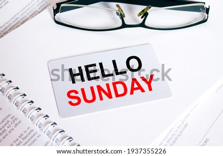Text Hello Sunday on a business card lying on a notepad with eyeglasses and text documents. Business concept