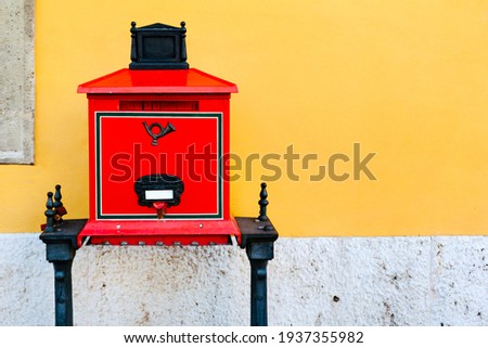 Red old mailbox against a yellow wall in Budapest