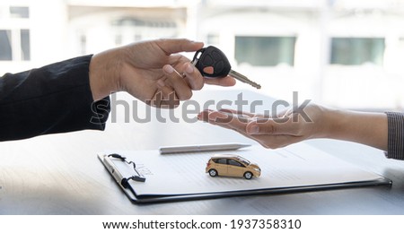 Car salesman gave the keys to the customers who signed the purchase contract legally, Successful completion of car sales, Purchase contract and key delivery. Royalty-Free Stock Photo #1937358310