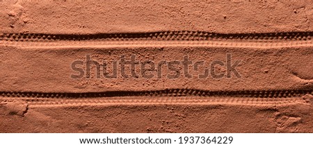 Tyre pattern on the reddish-orange sandy surface with copy space. Imitation of the traces of the rover on the planet Mars. Top view, banner Royalty-Free Stock Photo #1937364229