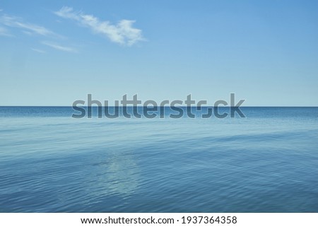 A small cloud above the calm and blue Baltic Sea horizon on the southwest coast of Latvia. Royalty-Free Stock Photo #1937364358