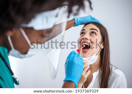 Close up of female health Professional in PPE introducing a nasal swab to a senior female patient at her house. Rapid Antigen Test kit to analyze nasal culture sampling while coronavirus Pandemic.