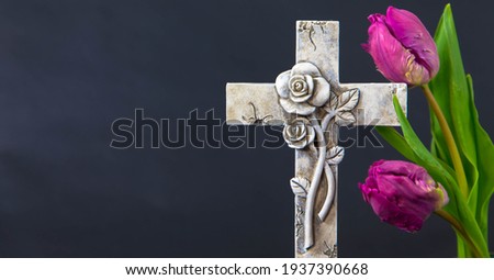 Decorated cross with a purple tulip flowers on a dark background. Condolence card. Plenty of copy space for religious sayings. Funeral and mourning concept. Royalty-Free Stock Photo #1937390668