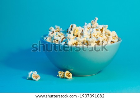 Bright pictures of popcorn. Popcorn in a blue plate. Blue background. Flat lay, copy space. Banner