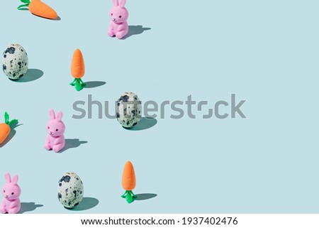Easter pattern made with eggs, easter bunny, carrots on blue background. Creative minimal holiday concept. Flat lay, top view, copy space.