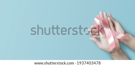 woman hands holding pink ribbon, breast cancer awareness, October pink, World cancer day concept