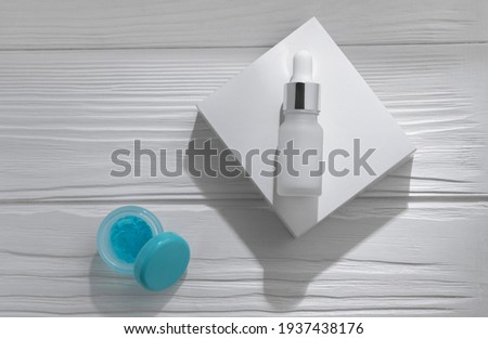 Pipette bottle on white box and open blue gel on white wooden table