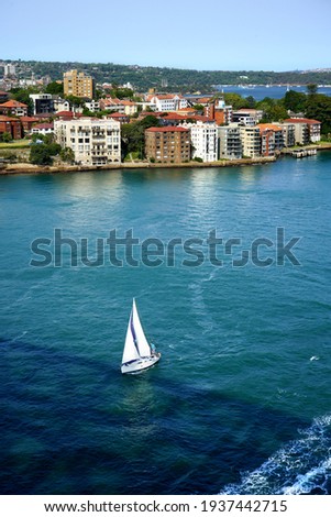 The shadow of Harbour Bridge, a sailboat and Kirribilli Suburbs in Sydney.
