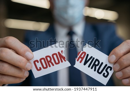 Close up of man's hands tearing paper with word coronavirus , selective focus. Stop virus concept Royalty-Free Stock Photo #1937447911