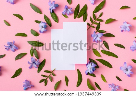 Two white business cards on a pink background with green leaves. Mockup for branding presentation