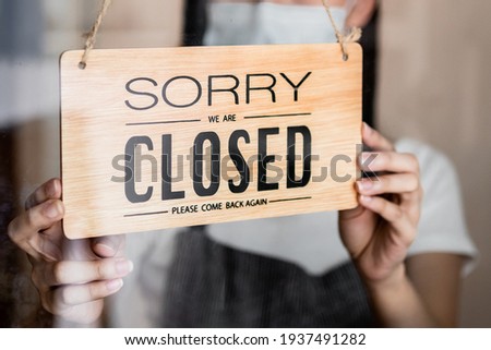 Young asian owner retail,coffee shop woman turning sign board to closed with wearing face mask,protection to pandemic of coronavirus.Close store,restaurant or pub due to lockdown, quarantine of covid. Royalty-Free Stock Photo #1937491282
