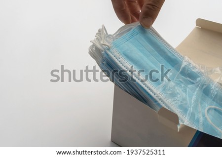 Surgical masks are stack and a paper box, isolated on white background.