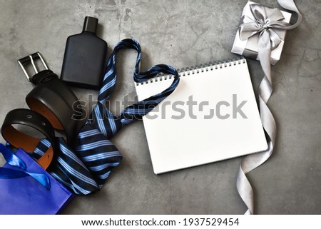 Creative composition. Belt, cologne, girt box, notepad with blue gift bag on a gray background. Greeting card. HAPPY FATHER'S DAY. Copy space. Flat lay.