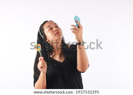 Fashion portrait young woman, lollipop, and mirror is having fun over white background.