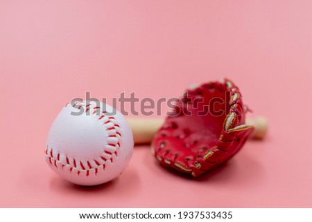 Baseball with glove and bat are on pink background