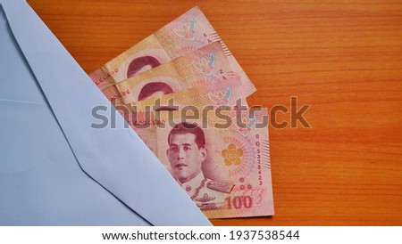 Thai baht currency with White envelope placed on the wooden floor.