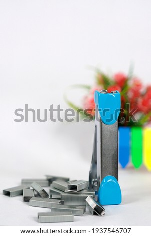 a blue stapler and group of staples on white background
                               
